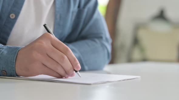 Close Up of Hand Writing on Paper with Pen alt