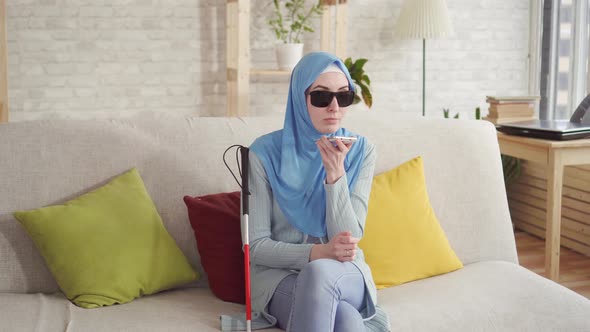 Beautiful Blind Muslim Girl in Hijab at Home,enjoys Smartphone alt