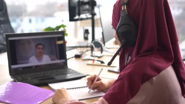 Muslim student video chats with teacher. Distance learning or Remote working alt