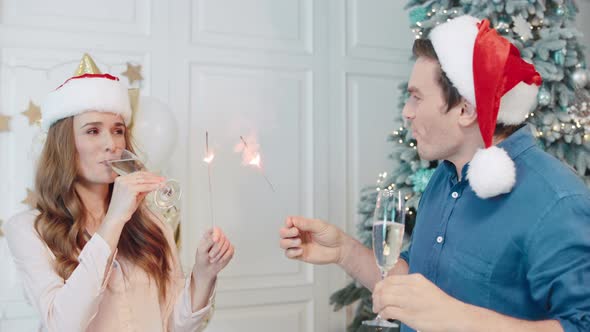 Cheerful Man and Woman Making Hobnob and Hugs in Santa Hats. alt
