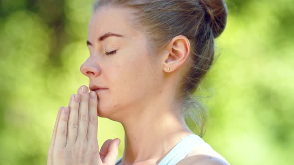 Concentrated young woman blonde meditates in yoga pose joining hands in namaste asana alt