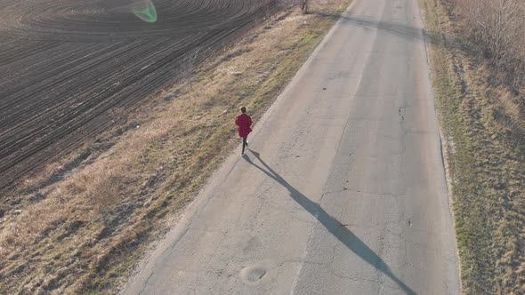 Aerial View of Woman Farmer with Digital Tablet Computer Looks at a Fresh Plowed Field After Winter alt