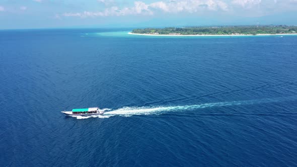 White and Blue Tourist Motorboat Sails on Ocean Past Island alt