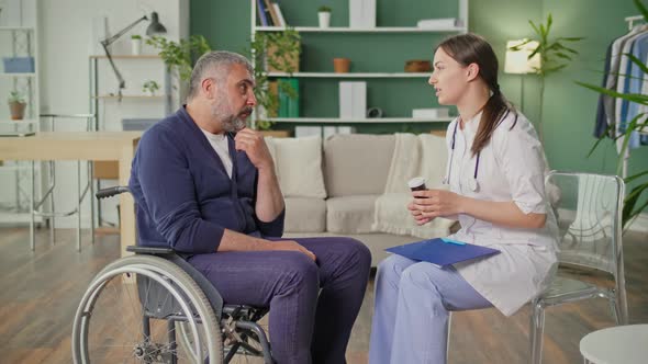 A Middleaged Man in a Wheelchair Talking to a Nurse alt