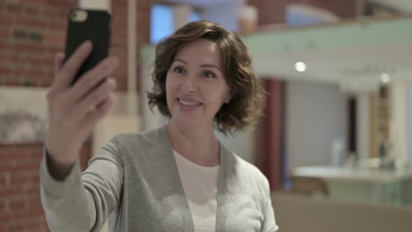 Portrait of Old Woman Taking Selfie on Smartphone alt