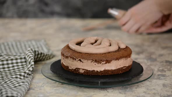 Pastry Chef Making A Cake On The Kitchen. Female Hand Squeezes The Chocolate Cream alt
