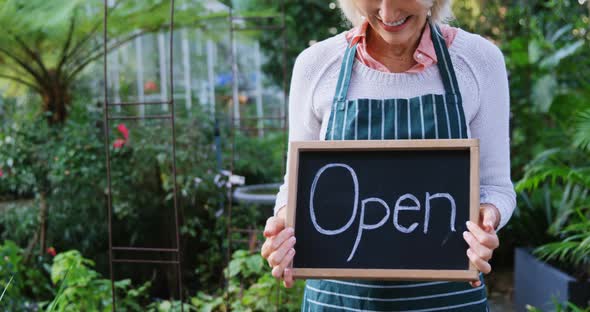 Mature woman holding open sign alt