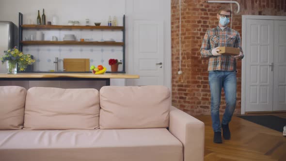 Man in Safety Mask and Gloves Receive Parcel Delivery at Home alt