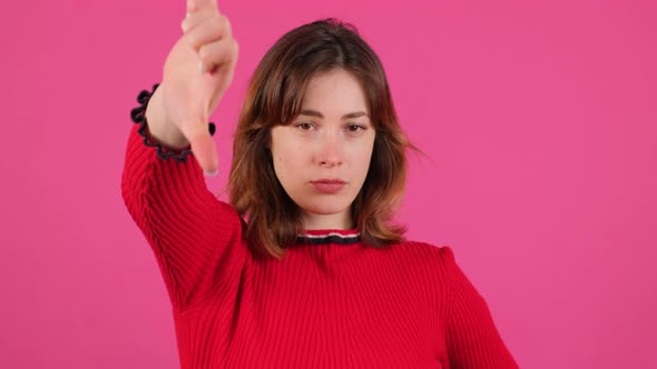 Portrait of a Discontented Young Girl Making a Thumbs Down Gesture alt