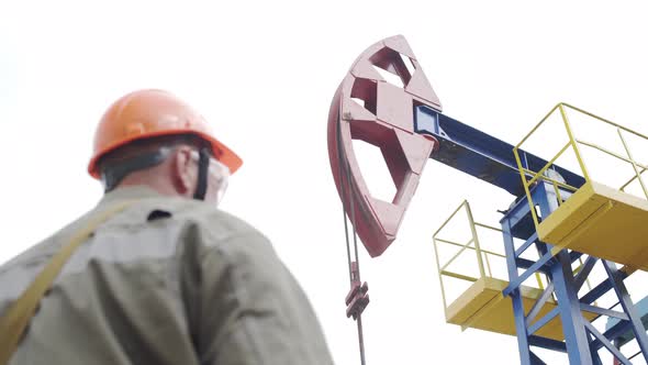 Silhouette of Man Engineer Overseeing Oil Pumping Unit in Site of Crude Oil Production. Industrial alt