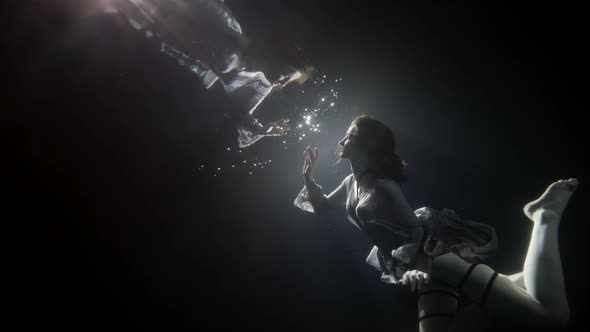 Young Woman Is Floating Underwater and Touching Reflection in Surface Magic Slow Motion Shot in Pool alt