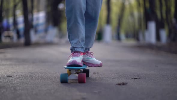 Close Up Legs Riding on Skateboard in Motion of Asphalt in Park