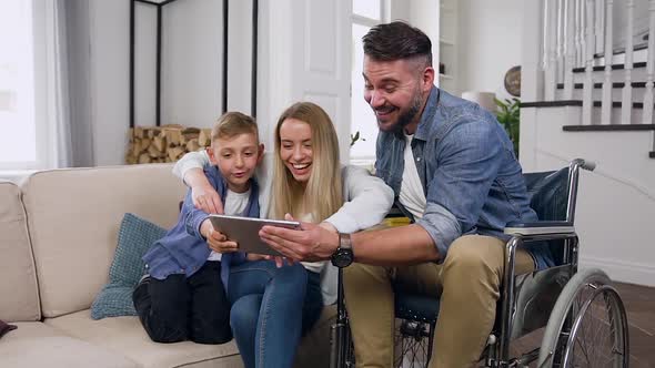 Friendly Mother, Son and Dad in Wheelchair which Celebrating Victory in Video Game alt