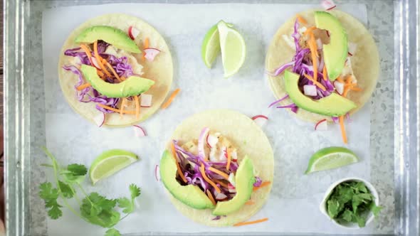 Fresh fish tacos with cod and purple cabbage on a white corn tortillas. alt