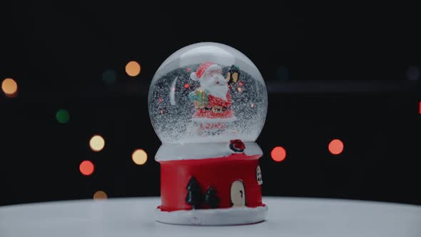 Glass Ball with Santa Claus on a Background of Lights