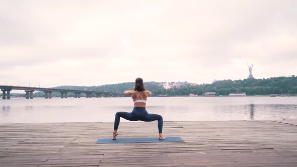 Girl Doing Yoga Exercises By the City River alt
