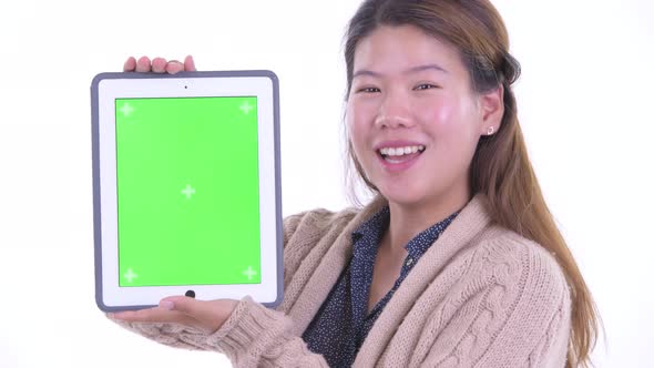Face of Happy Young Asian Woman Showing Digital Tablet Ready for Winter alt
