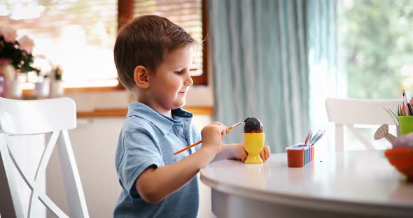 Cute Little Boy Painting Easter Eggs at Home