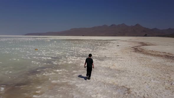 Single Man Walking Lonely on White Urmia Salt Lake in Iran