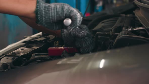 Skillful Asian guy in uniform fixing car at mechanics garage at night. alt