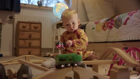 CUTE baby watching a toy train before managing to catch and study it alt