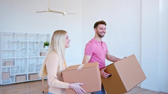 Romantic couple man and long haired lady carries cardboard boxes and walks to large pile alt