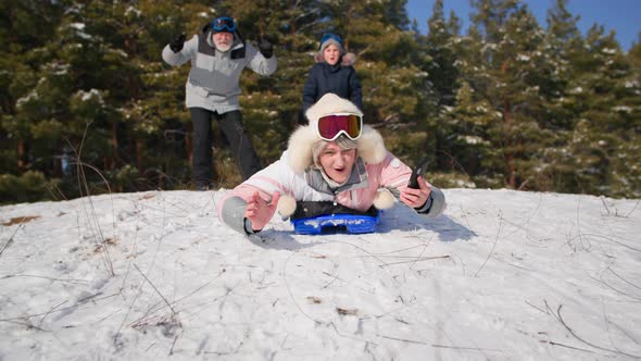 Cheerful Retired Women Have Fun Leading an Active Lifestyle Sledding Down Snowy Slope While Relaxing