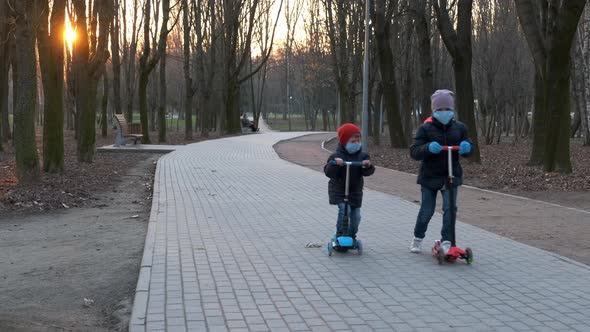 Little boy and girl in medical masks ride scooters in the Park