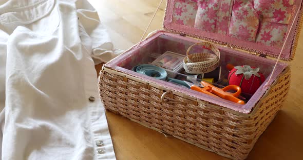A sewing kit with pin cushion, tape measures, needle and thread on a table for a seamstress to repai alt