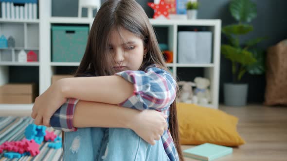 Portrait of Mad Moody Child Sitting on Floor Alone Expressing Anger and Offence alt