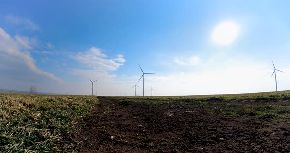 Motion Timelapse Of Wind Turbines At The Field On A Sunny Day. low level, wide GoPro shot alt