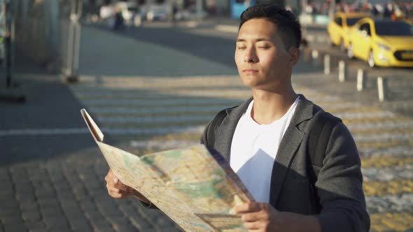 Left To Right Pan Real Time Portrait Shot of a Young Asian Man Looking at a Map. Moscow Is the