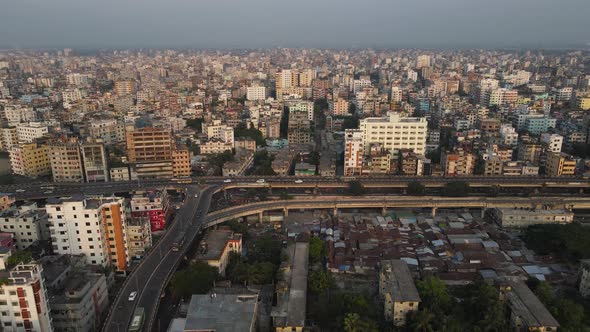 Aerial drone shot of Dhaka showing flyover and traffic with densely populated city buildings. alt