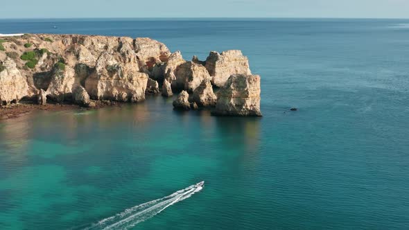 Motorboat Driving in Atlantic Ocean at Rocks of Ponta De Piedade Portugal alt