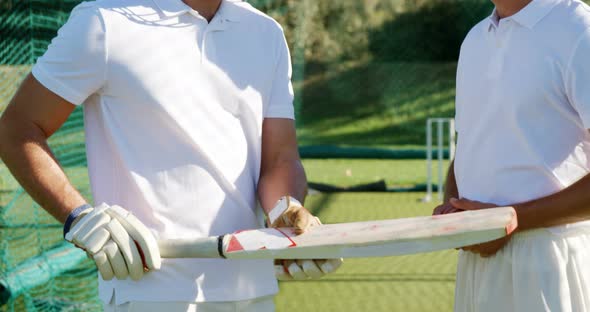 Cricket players interacting with each other during a practice session in the nets alt