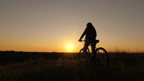 Free Girl Travels with a Bicycle at Sunset. Concept of Adventure and Travel. Hiker Healthy Young alt