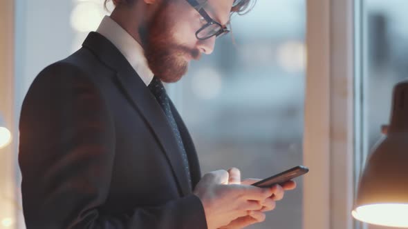 View through Glass Wall of Businessman Typing on Phone and Answering Call alt