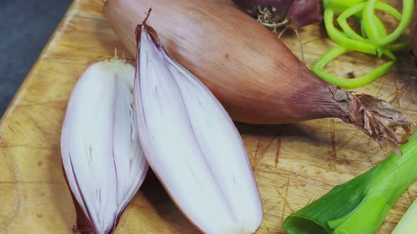 Different types of onion on wooden table. Onions, shallots, red and spring onions variety.