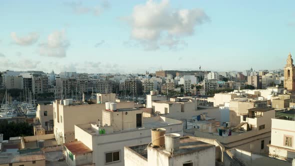 Dolly Forward Over Roof Terrace Revealing Port of Mediterranean City Town on Malta Island in Brown alt