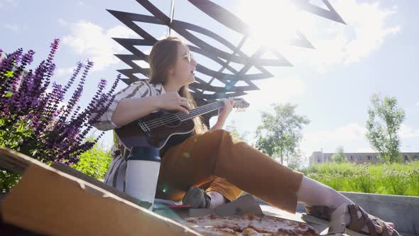 Women Take Slices of Pizza Sitting on Bench in City Park