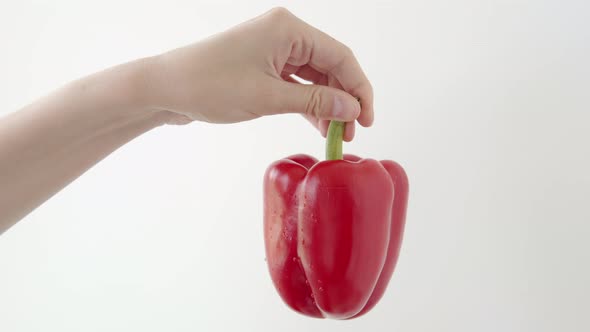 Vegetarian Girl Buyer Customer of the Store Shows a Ripe Red Pepper on a White Background
