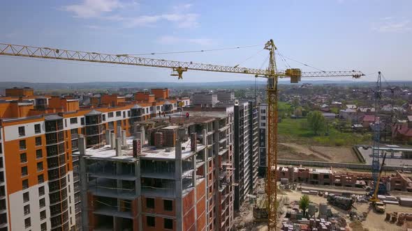 Aerial view of high modern residential building and tower crane under construction. alt