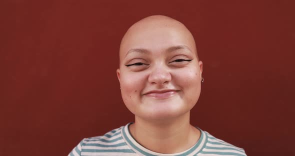 Bald girl posing and smiling in front of camera - Real people, diversity and female power concept alt
