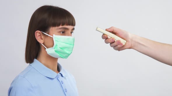 Young Woman in Respiratory Protection Mask Looking To Side and Doctor Arm Measure Her Body alt