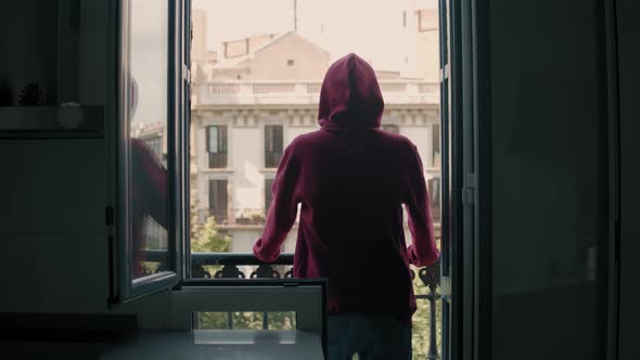 Isolated and Depressed Millennial Teen Man Watching the Empty Streets From His Balcony in Sadness alt