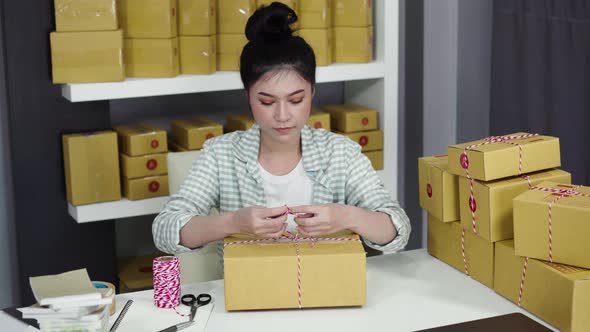 woman entrepreneur are tying ropes and packing products in parcel box, prepare for delivery