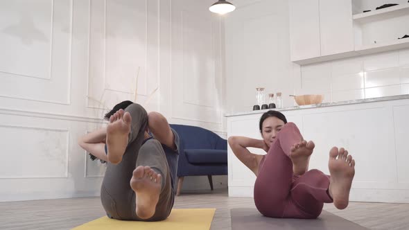Asian couple pumping the abdominal exercise on yoga mat at home