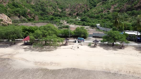 Aerial drone of blue bus vehicle driving along a coastal tree lined road on tropical island Timor Le alt
