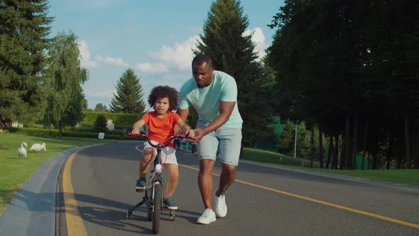 Loving Father Teaching Son To Ride Bicycle in Park alt