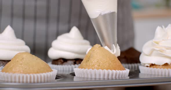 Confectioner decorating cupcake with whipped buttercream alt